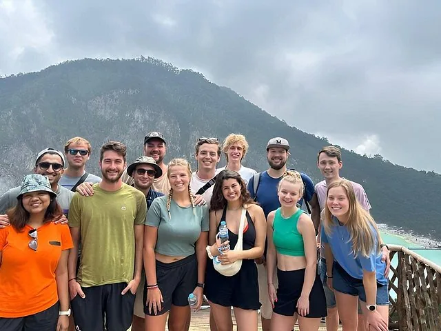 Grupo de turistas posando para una foto con vistas al lago del cráter Kawah Putih.