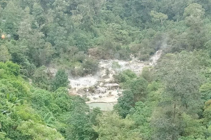 View from above of volcanic landscape with small structures nestled in trees.
