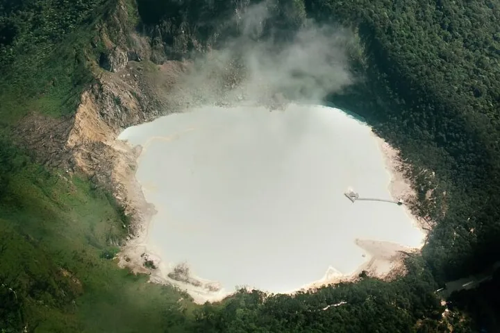 Vista aérea del lago del cráter blanco sulfúrico de Kawah Putih emitiendo vapor.